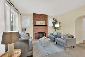 Living room featuring a fireplace, carpet floors, and plenty of natural light