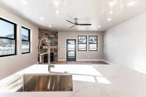 Unfurnished living room with plenty of natural light, ceiling fan, a stone fireplace, and sink