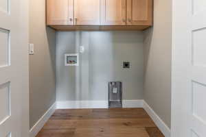 Clothes washing area with electric dryer hookup, cabinets, and washer hookup