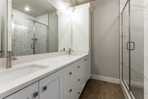 Bathroom featuring wood-type flooring, vanity, and a shower with shower door