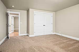 Unfurnished bedroom featuring a textured ceiling, carpet floors, and a closet