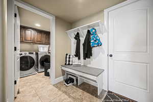 Laundry room with cabinets, light tile patterned flooring, and washing machine and dryer