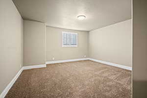 Empty room with carpet and a textured ceiling