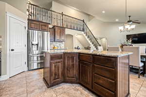 Kitchen with backsplash, dark brown cabinetry, stainless steel fridge with ice dispenser, and a kitchen island