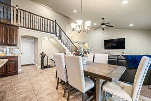 Tiled dining space featuring lofted ceiling and ceiling fan with notable chandelier