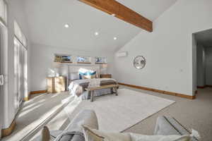 Carpeted bedroom with high vaulted ceiling, beam ceiling, and a wall mounted air conditioner