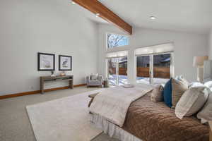 Bedroom with vaulted ceiling with beams, carpet floors, and access to outside