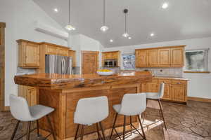 Kitchen with decorative light fixtures, a center island, a kitchen bar, decorative backsplash, and stainless steel appliances