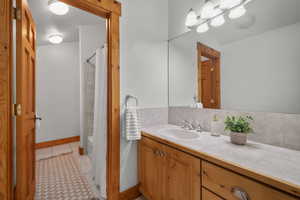 Bathroom featuring shower / bath combo with shower curtain, tile patterned floors, and vanity