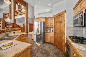 Kitchen with stainless steel appliances, tile counters, backsplash, a wall mounted air conditioner, and sink