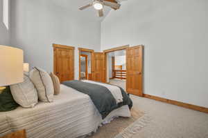 Carpeted bedroom featuring ceiling fan and high vaulted ceiling