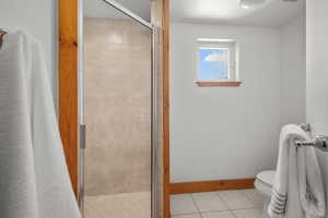 Bathroom with toilet, a shower with curtain, and tile patterned floors