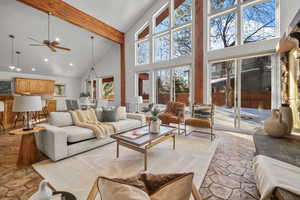 Living room featuring ceiling fan, a high ceiling, and beam ceiling