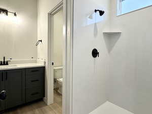 Bathroom featuring a shower, toilet, vanity, and hardwood / wood-style flooring