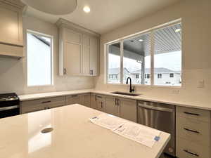 Kitchen with backsplash, gas range, sink, dishwasher, and gray cabinets