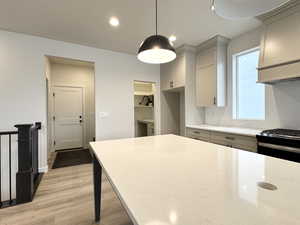 Kitchen with decorative backsplash, light hardwood / wood-style flooring, gas range oven, and hanging light fixtures