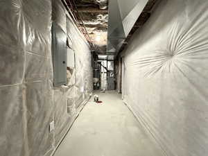 Basement with heating unit, water heater, and electric panel