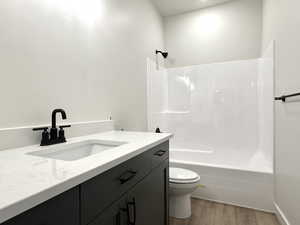 Full bathroom featuring shower / bathing tub combination, hardwood / wood-style floors, vanity, and toilet