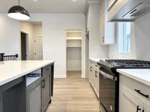 Kitchen featuring premium range hood, gray cabinetry, gas range oven, white cabinetry, and hanging light fixtures