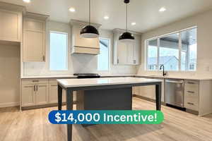 Kitchen featuring sink, light hardwood / wood-style flooring, appliances with stainless steel finishes, hanging light fixtures, and decorative backsplash