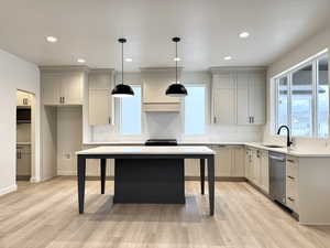 Kitchen featuring dishwasher, pendant lighting, a center island, and light hardwood / wood-style flooring