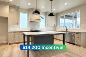 Kitchen with sink, hanging light fixtures, plenty of natural light, appliances with stainless steel finishes, and light wood-type flooring