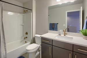 Full bathroom with tile patterned floors, vanity, shower / bathtub combination with curtain, and toilet