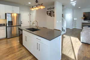 Kitchen with pendant lighting, white cabinets, sink, stainless steel fridge, and black dishwasher