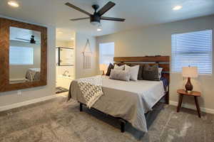 Primary Bedroom featuring en-suite bathroom, ceiling fan, and carpet floors