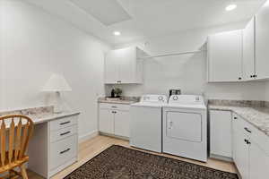 Basement Laundry area with washer and dryer, light hardwood / wood-style floors, and cabinets. Second laundry area in the home.