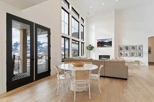 Dining room with a large fireplace, a towering ceiling, and light wood-type flooring