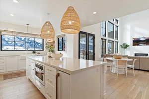 Kitchen featuring white cabinetry, sink, oven, decorative light fixtures, and a fireplace