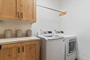 Washroom featuring washer and clothes dryer and cabinets