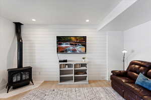 Living room with light hardwood / wood-style floors, a wood stove, and wooden walls