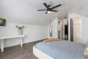 Bedroom featuring ensuite bathroom, ceiling fan, dark wood-type flooring, and lofted ceiling