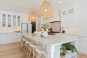 Kitchen with white cabinets, high end white fridge, backsplash, and custom range hood