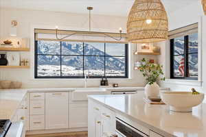 Kitchen featuring white cabinetry, light stone countertops, sink, and a mountain view