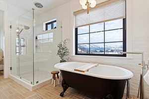 Primary Bathroom featuring a mountain view, shower with separate bathtub, plenty of natural light, and tile walls