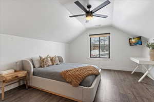 Bedroom with ceiling fan, dark hardwood / wood-style flooring, brick wall, and vaulted ceiling