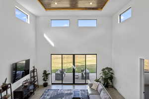 Living room with a high ceiling, a raised ceiling, and a wealth of natural light