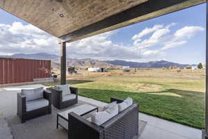 View of patio with a mountain view, ceiling fan, a rural view, and an outdoor living space