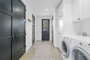 Laundry area featuring washing machine and dryer and cabinets