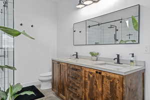 Bathroom with vanity, an enclosed shower, and toilet