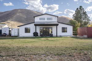 Back of property with a mountain view and a lawn