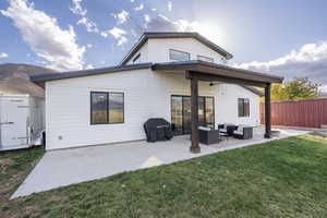 Back of house with a lawn, an outdoor living space, and a patio area