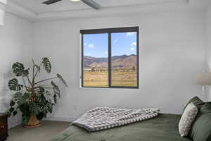 Bedroom with a mountain view, multiple windows, ceiling fan, and carpet flooring