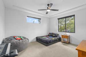 Bedroom with carpet, ceiling fan, and a raised ceiling