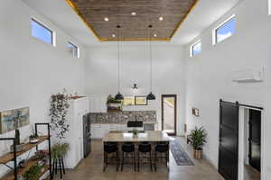 Dining area with an AC wall unit, a barn door, a raised ceiling, and wooden ceiling