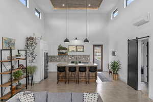 Kitchen with a wall mounted AC, pendant lighting, a barn door, a high ceiling, and white cabinetry