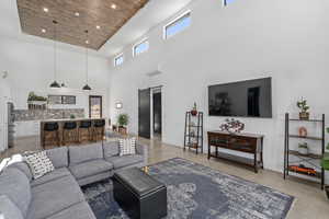 Living room featuring wood ceiling, a raised ceiling, ceiling fan, a barn door, and a high ceiling